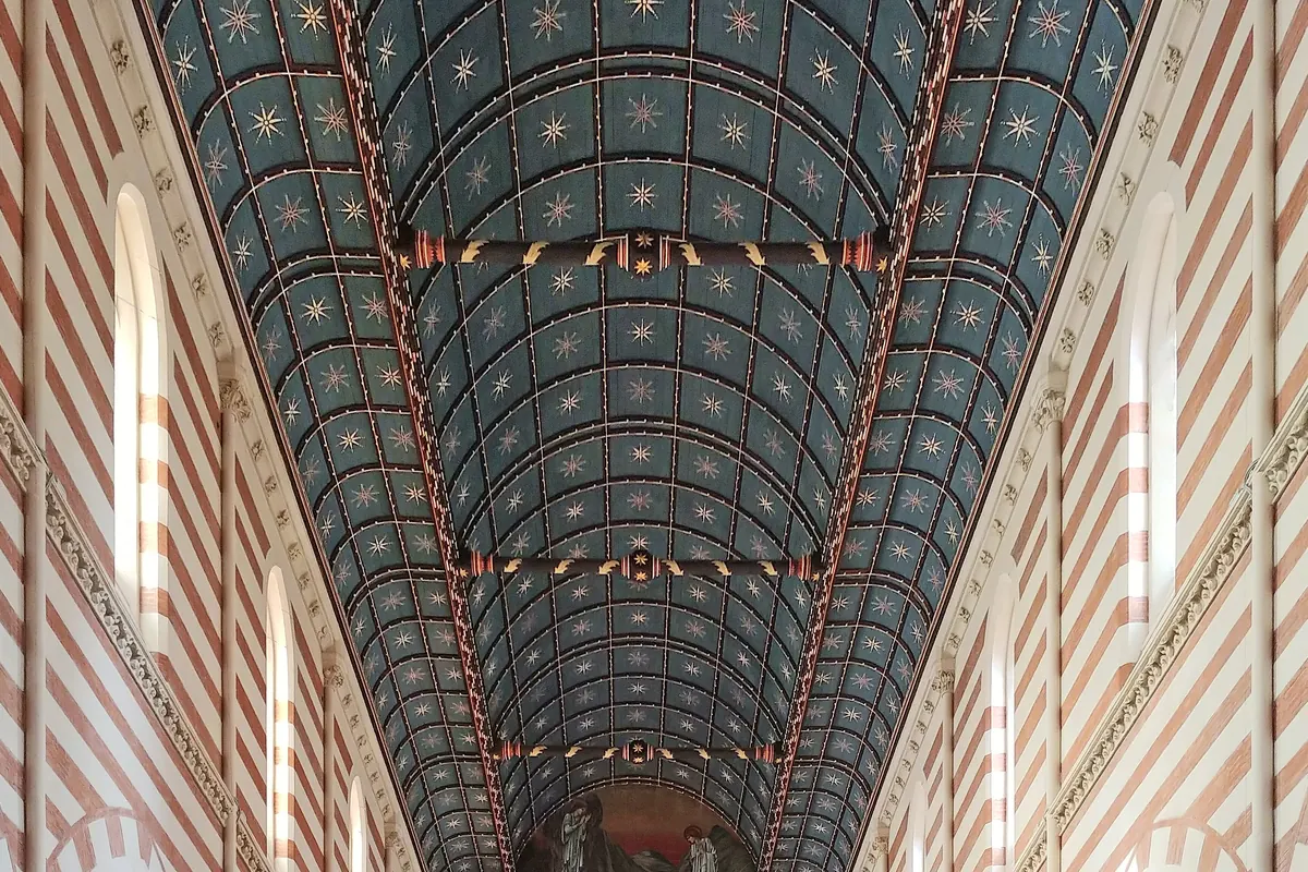 The deep blue barrel-vaulted ceiling of the church, studded with gold stars and framed by red and white striped walls.